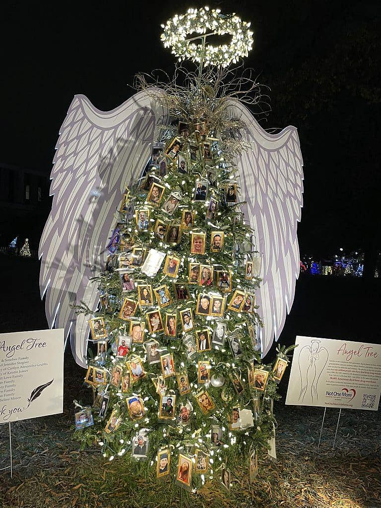 Christmas tree decorated with photos of loved ones lost, flanked by angel wings.