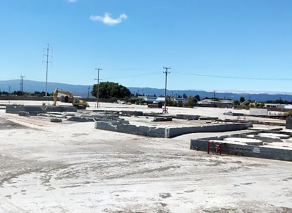 Concrete foundation and construction equipment on a large flat site.