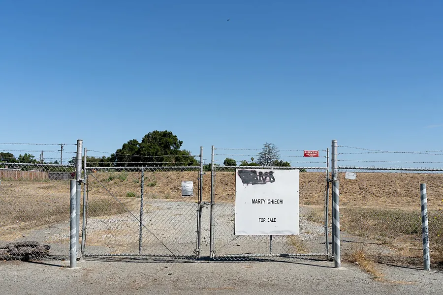 Barbed wire fence with a “For Sale” sign on a dry lot.