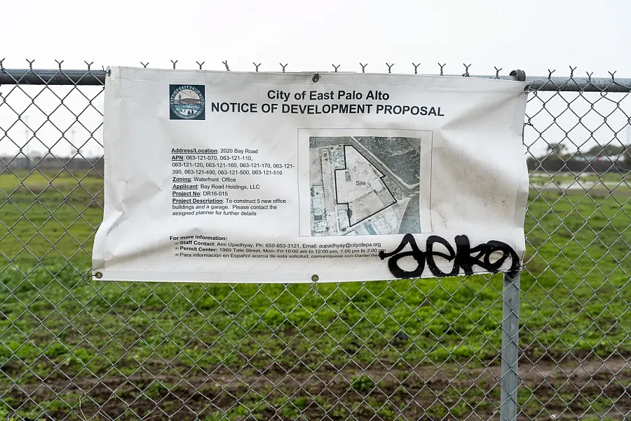 Development notice on a fence in front of a green field.