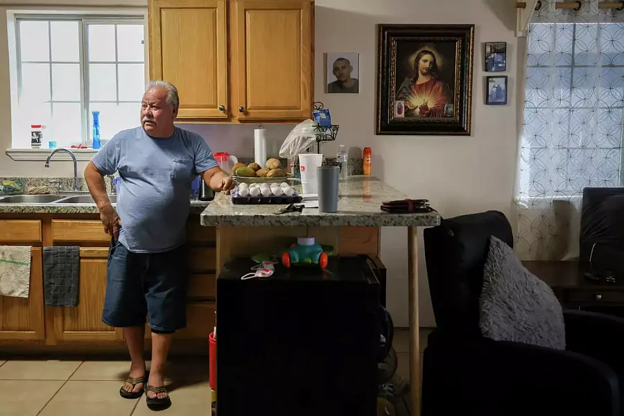 Image of a person watching TV, standing near kitchen counter, near image of their son