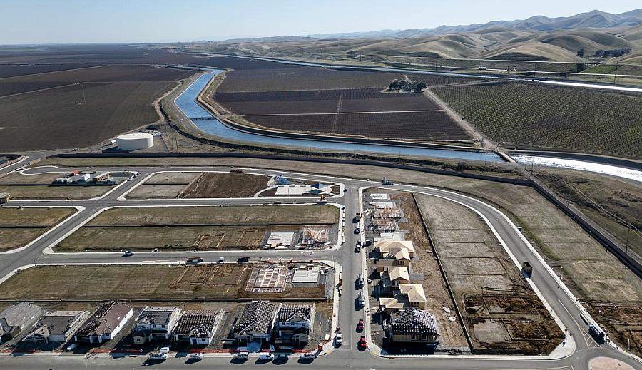 Aerial view of new housing development — Rows of homes under construction next to farmland and a canal.