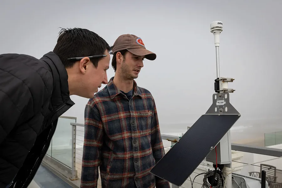 Two persons looking at a device that monitors air quality