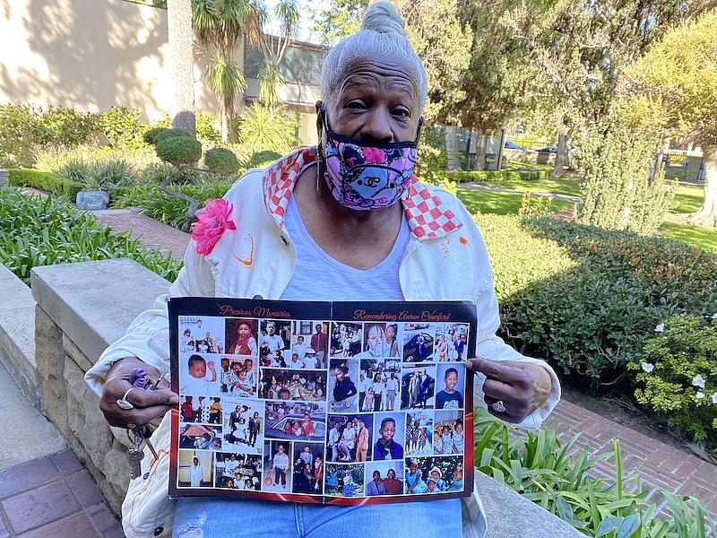 An old lady holding a poster of family photos