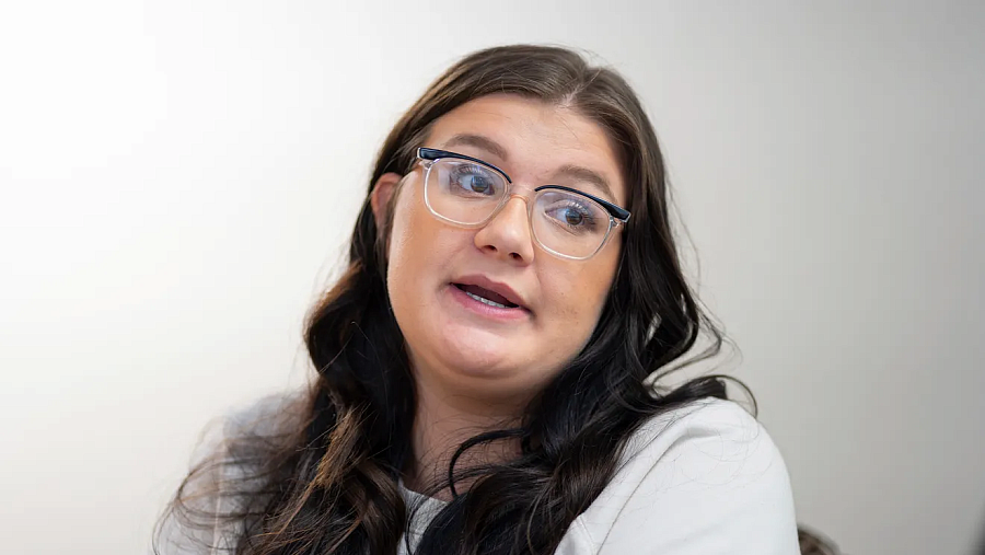 Person in white top with black hair and glasses
