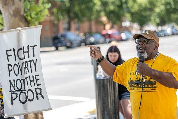 Person with yellow t-shirt speaking on a mic at a campaign