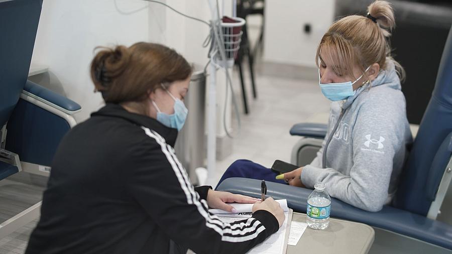 Two people with masks, one signing in the other