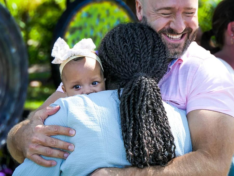 Image of a person hugging a mother and mother is holding a child