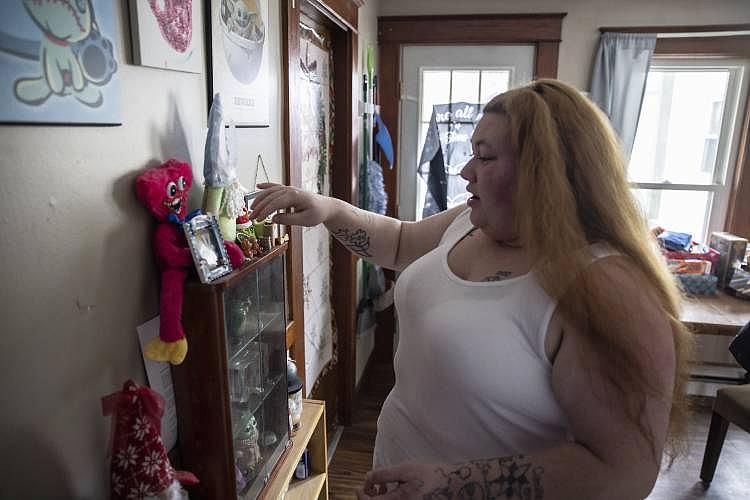Woman reaches for items on a shelf beside colorful toys.