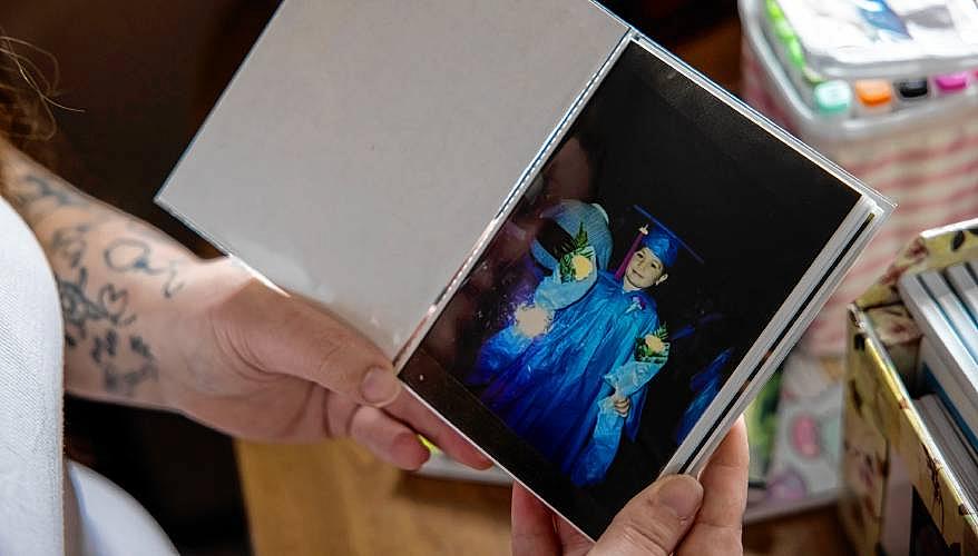 Hands hold a photo of a child in graduation gown.