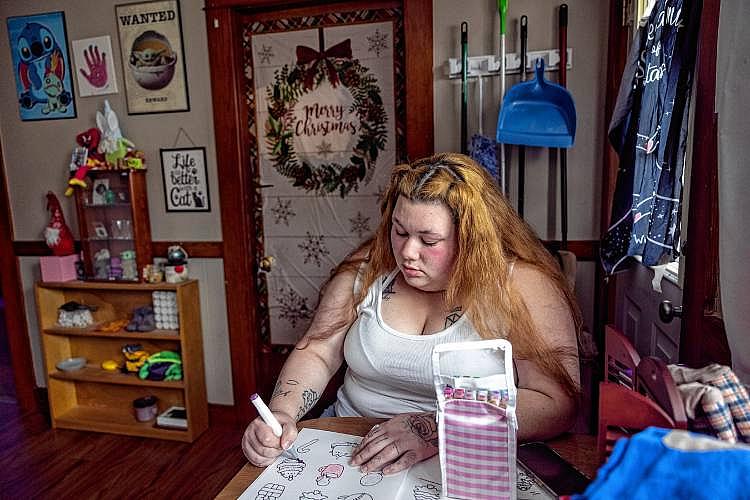 Woman draws at a table near holiday decor.