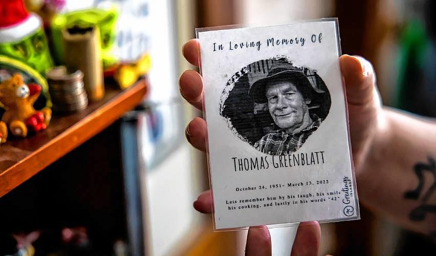 Hand holds a memorial card for Thomas Greenblatt.
