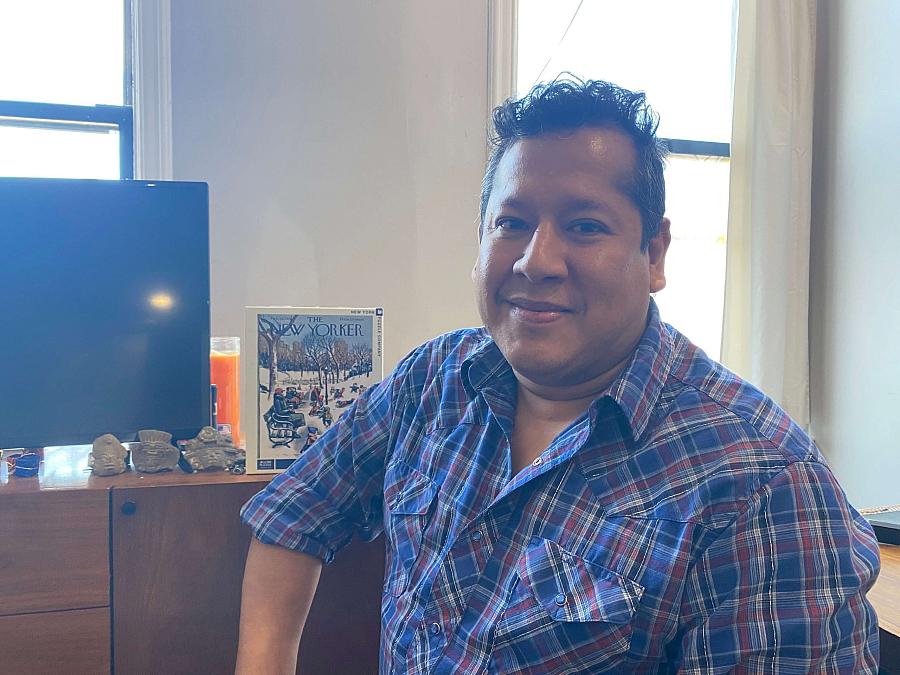 Person smiling at camera sitting on a desk near monitor