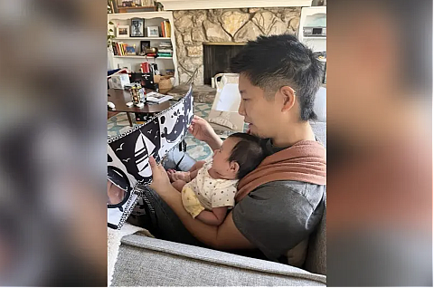 A person with infant in their laps while reading 