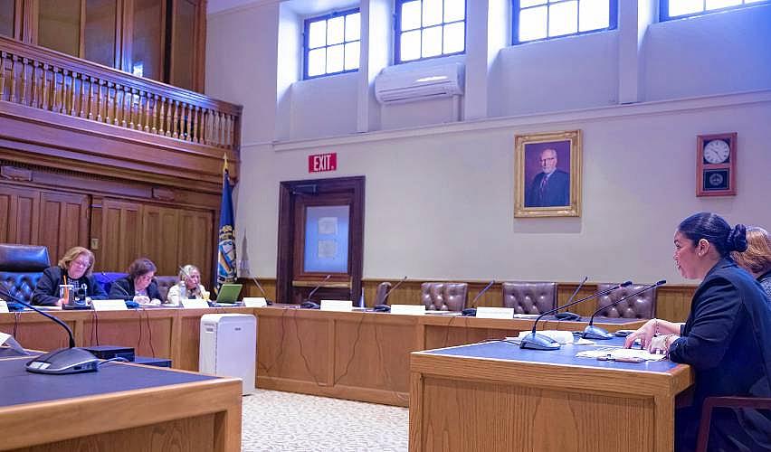 Person sitting in courtroom in front of a panel