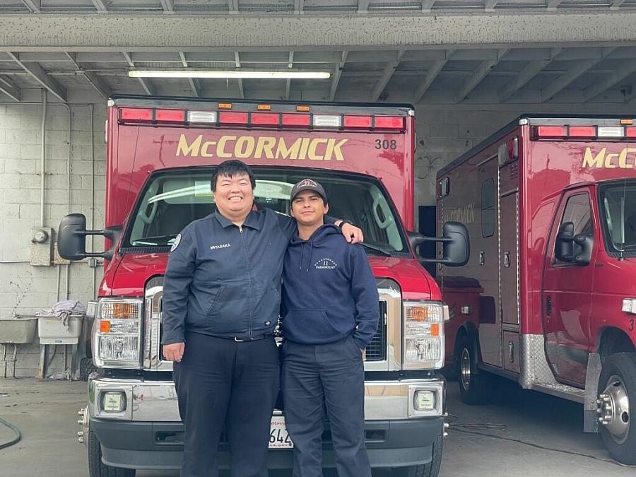 Image of 2 people posing in front of an ambulance