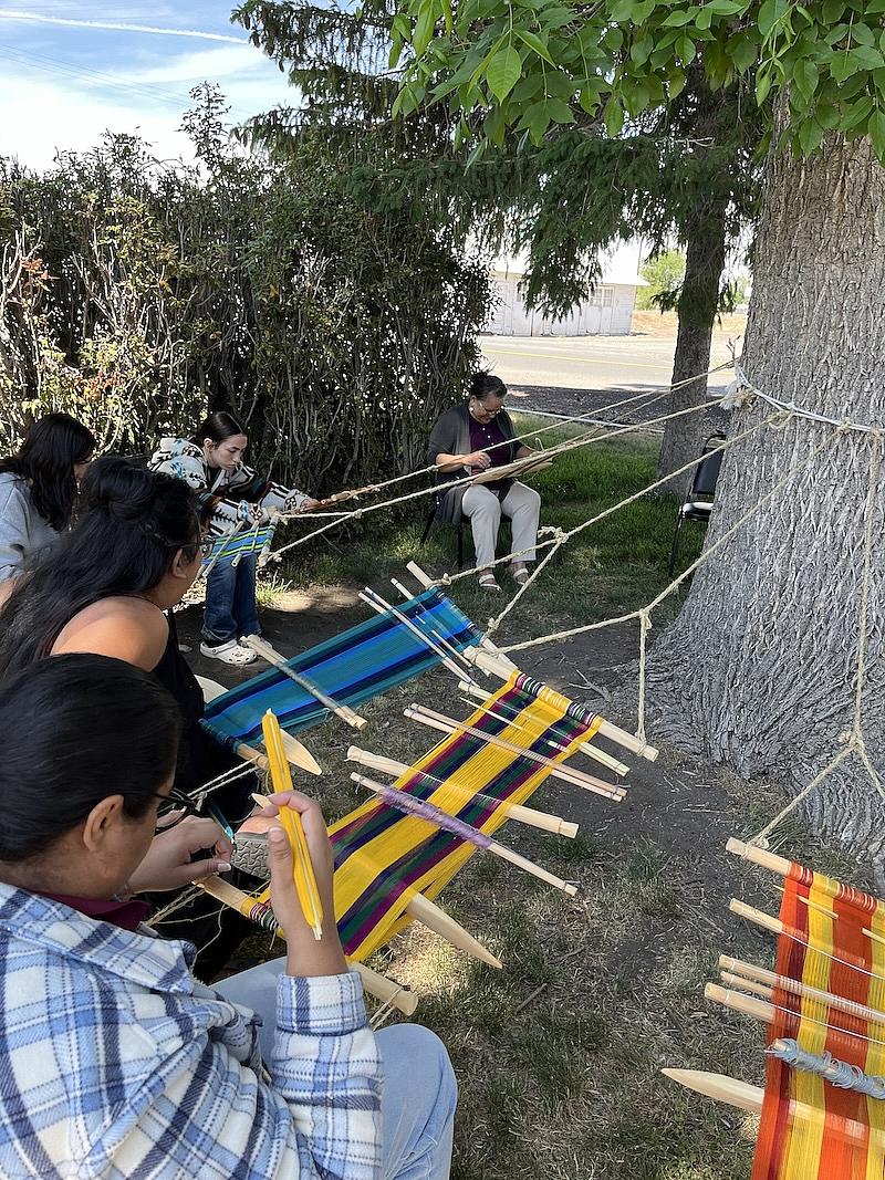 People seated around a tree working on textiles