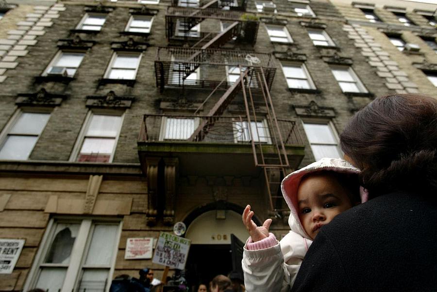A person holding baby in front of the building