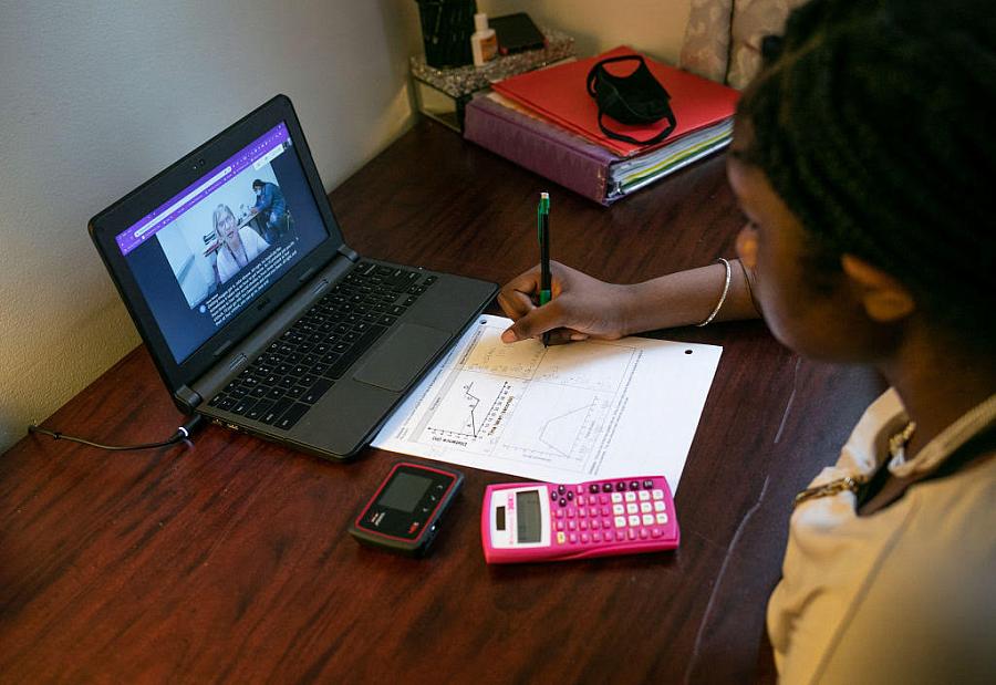 Person writing while watching something on a laptop