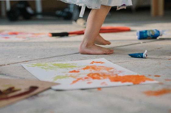 Paintings on the floor, a child standing nearby
