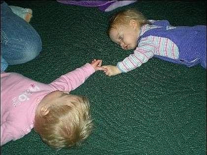 Two toddlers holding hands on the ground
