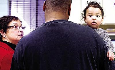 A healthy Kaelani Bobo looks out from her father Byron's arms as Dr. Michelle Simon talks to him about proper nutrition and exercise for youngsters (Shmuel Thaler/Sentinel)