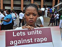 Photo: Flickr user, GovernmentZA Black woman with sign that reads, "Let's unite against rape."