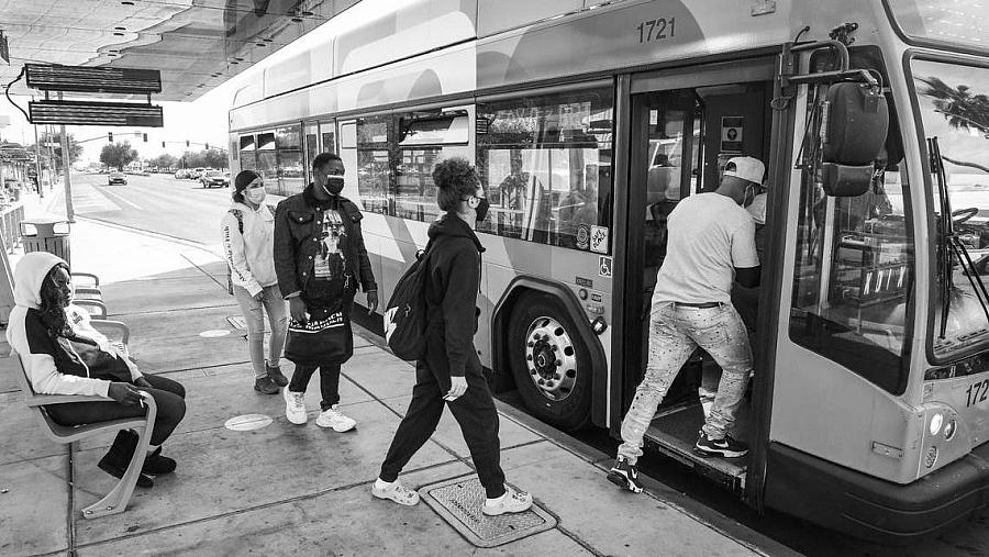 Passengers board a bus at a stop near Manchester Center in Fresno. 