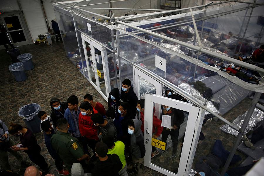 Minors talk to an agent outside a pod at the Department of Homeland Security holding facility run by the Customs and Border Patrol on March 30, 2021 in Donna, Texas, the main detention center for unaccompanied children coming across the U.S. border in the Rio Grande Valley. Minors talk to an agent outside a pod at the Department of Homeland Security holding facility run by the Customs and Border Patr