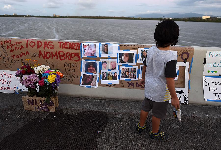 Un niño observa las fotos de mujeres víctimas de feminicidios que se colocaron como homenaje en el puente Teodoro Moscoso