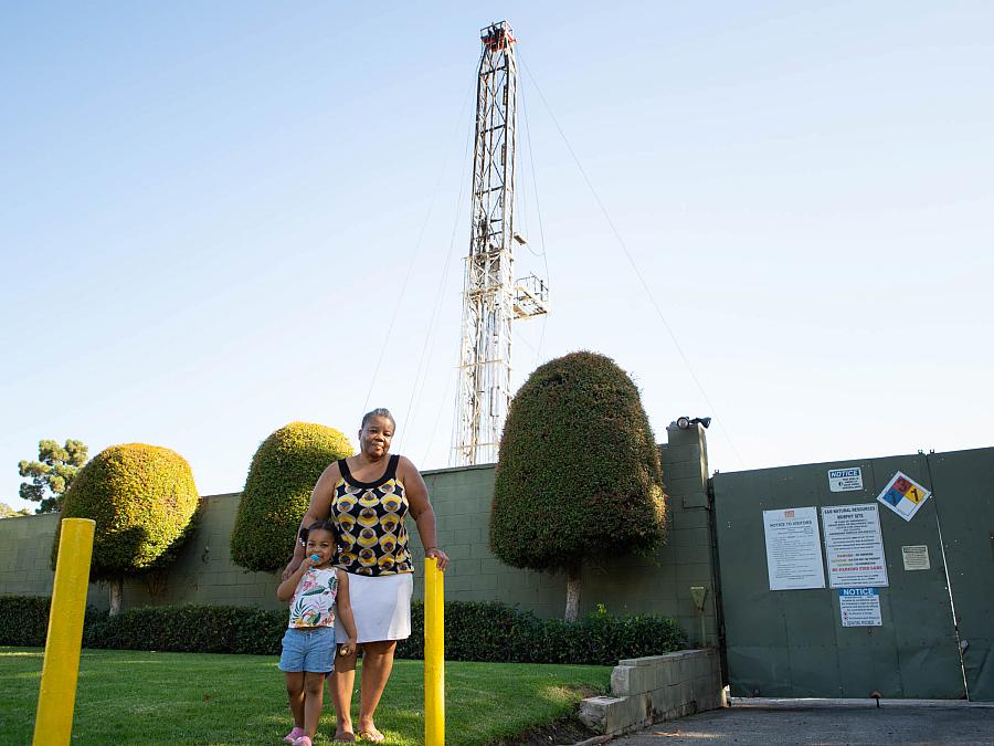 Deborah Bell-Holt and her granddaughter stand near an oil drilling site by her South Los Angeles home. A growing body of science has found strong overlap between environmental exposures and poor infant and maternal health outcomes. Deborah Bell-Holt and her granddaughter stand near an oil drilling site by her South Los Angeles home. A growing body of science