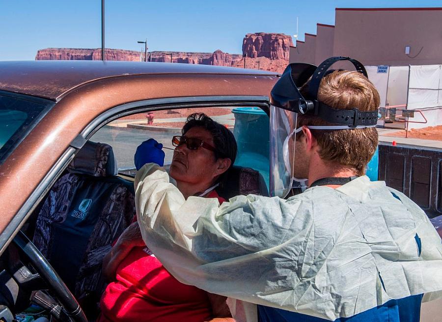 A nurse takes a swab sample from a Navajo Indian woman complaining of virus symptoms at a COVID-19 testing center at the Navajo 