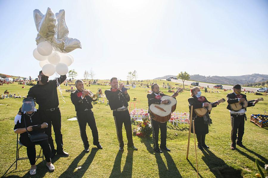 Rosa Mejia (L) listens as a mariachi band plays during a burial service for her husband Gilberto Arreguin Camacho, 58