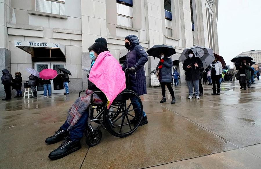 People line up in the rain outside the Yankee Stadium on February 5, 2021 in New York as the Stadium is turned into a mass Covid