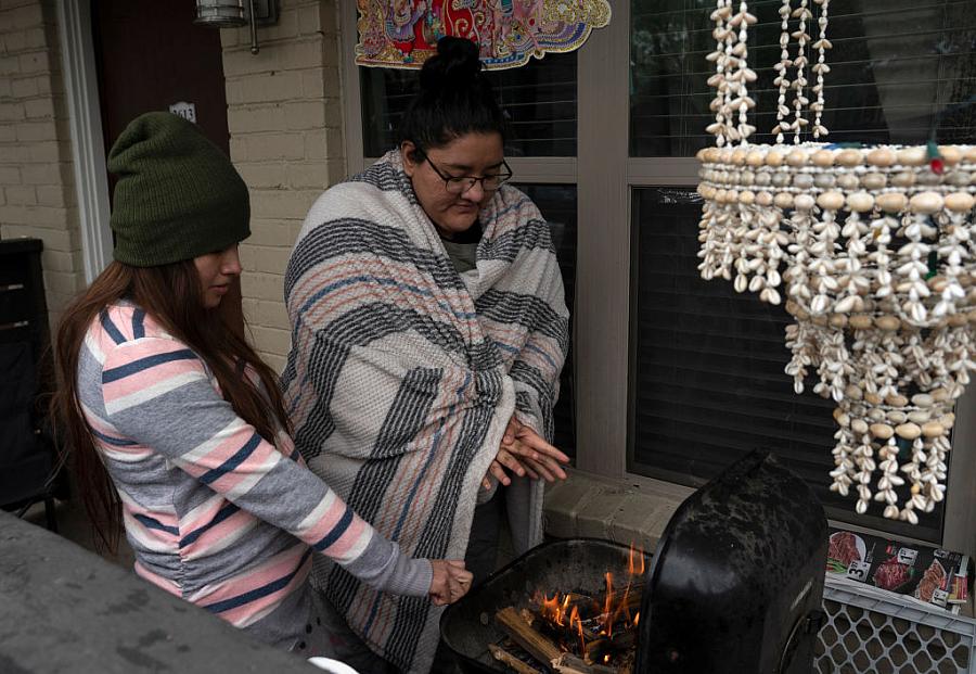  Karla Perez and Esperanza Gonzalez warm up by a barbecue grill during power outage caused by the February winter storm.