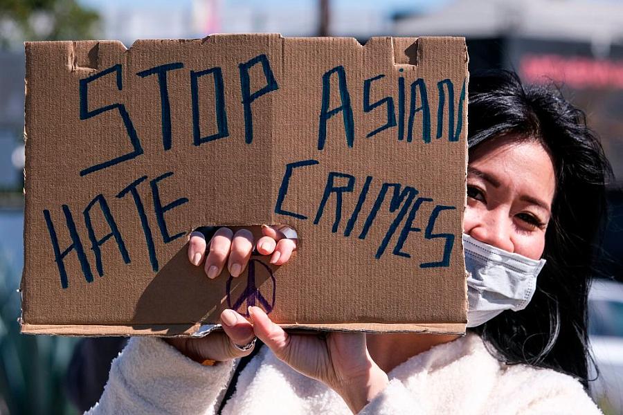 A demonstrator wearing a face mask and holding a sign takes part in a rally to raise awareness of anti-Asian violence