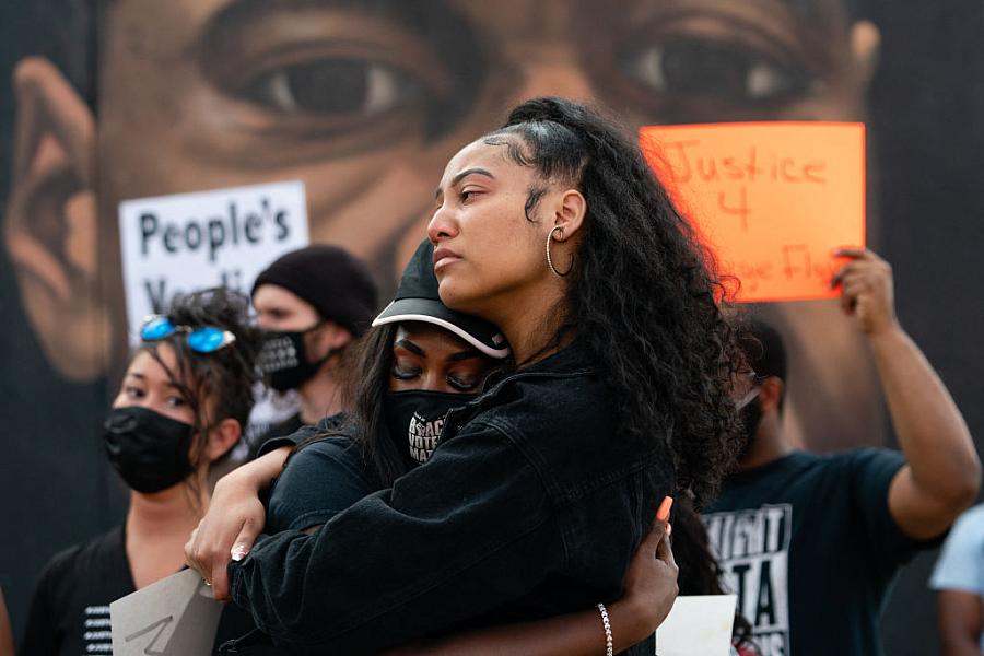 Two women embrace in front of a mural of George Floyd following the guilty verdict the trial of Derek Chauvin