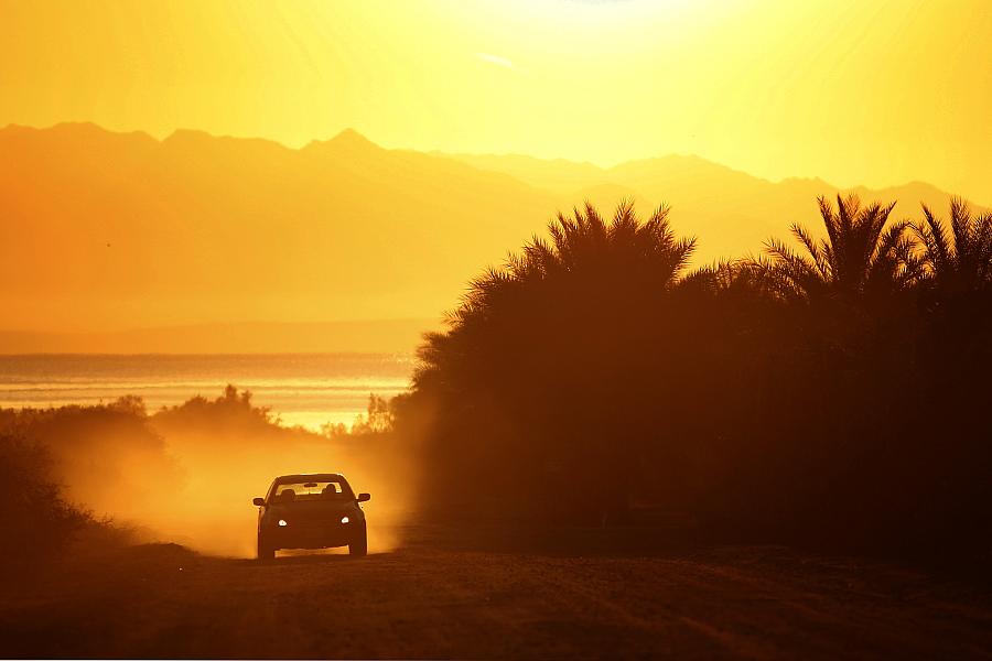 A car drives down a dusty road near the Salton Sea.