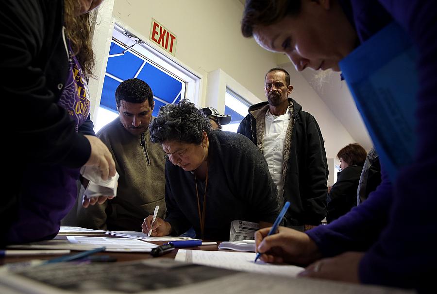 Attendees at a health insurance enrollment fair in Richmond, California fill out paperwork. (Photo by Justin Sullivan/Getty Imag