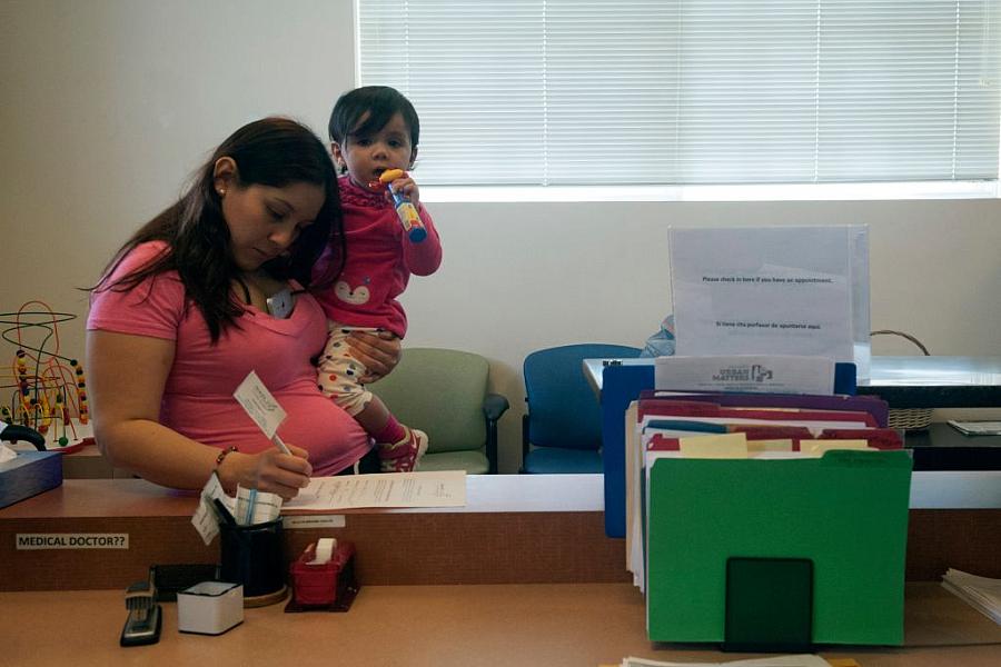 Alexandra Olivares fills out paperwork during a visit at Inner City Health Center in Denver, a clinic that offers medical, denta