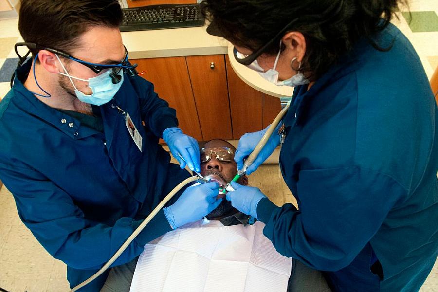 Dr. Luke Johnson (L) and dental assistant Rita Garcia treat patient Phillip Malone at Inner City Health Center in Denver, CO. 