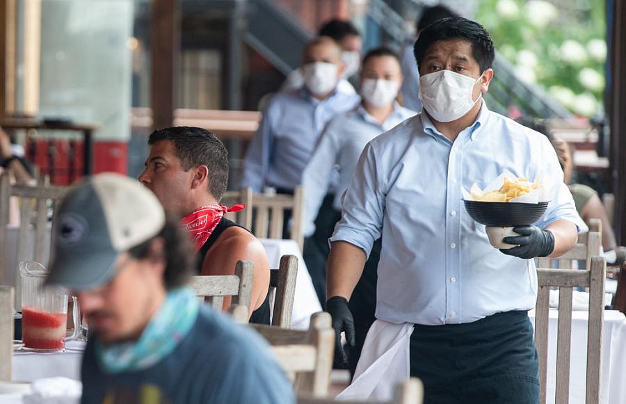 Waiter deliver food to a table to customers seated at an outdoor patio at a Mexican restaurant in Washington, D.C. on May 29.