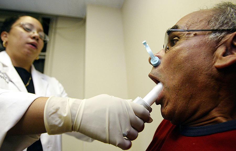 A man exposed to air pollutants near Ground Zero after Sept. 11 inhales deeply before blowing into a spirometer to check for air