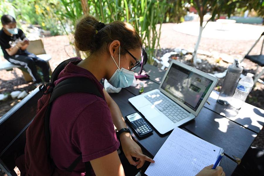 A student sits in a community garden near her home in the Boyle Heights neighborhood of Los Angeles. In-person classes remain on