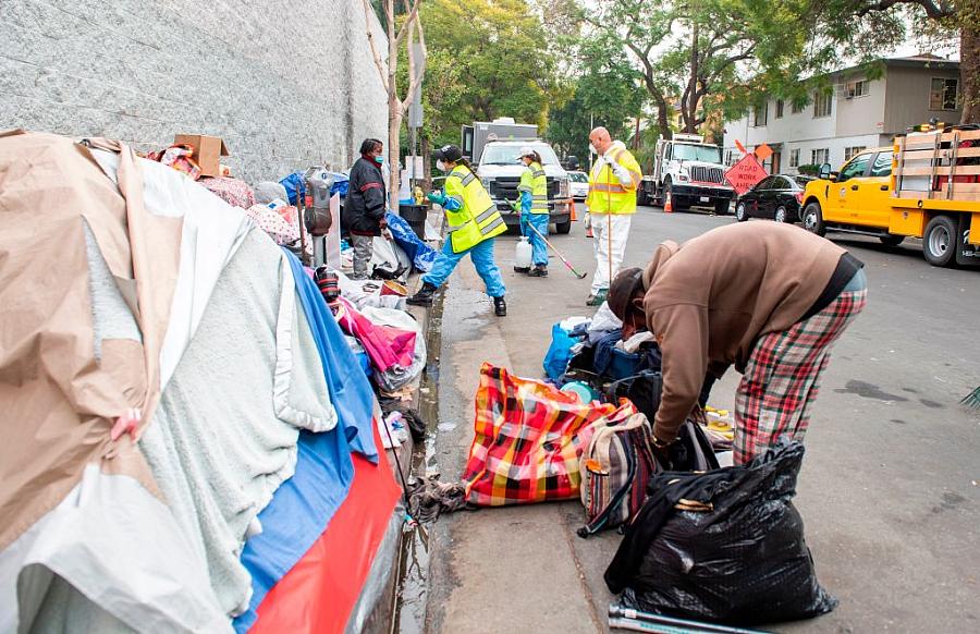 An unhoused resident of Los Angeles tries to protect his belongings amid a clean-up effort by city workers in February, 2021.