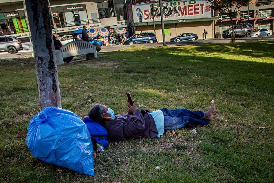 A homeless man lies on the grass in MacArthur Park in Los Angeles in May.