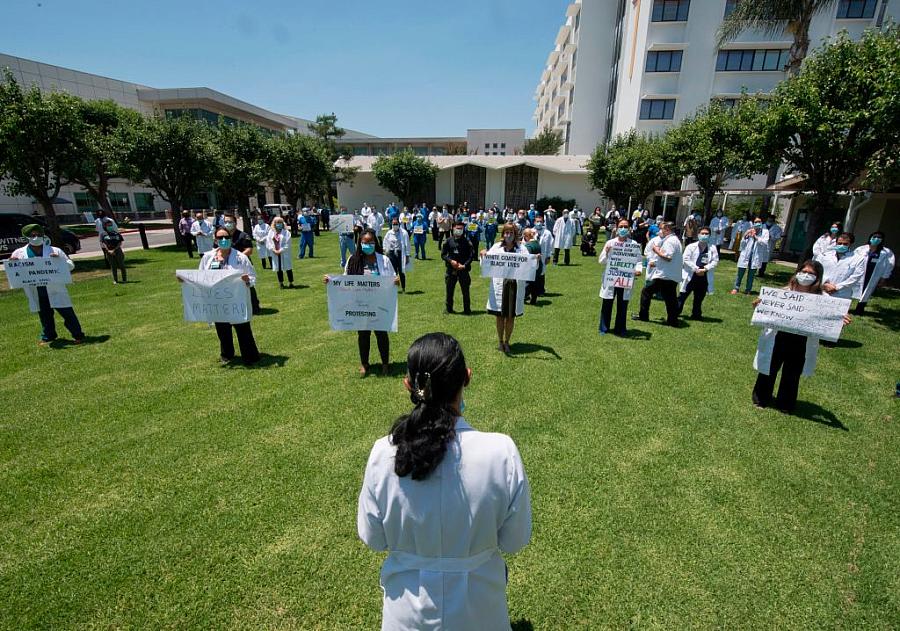 Health care workers participate in a “White Coats for Black Lives” event in solidarity with George Floyd and other black America