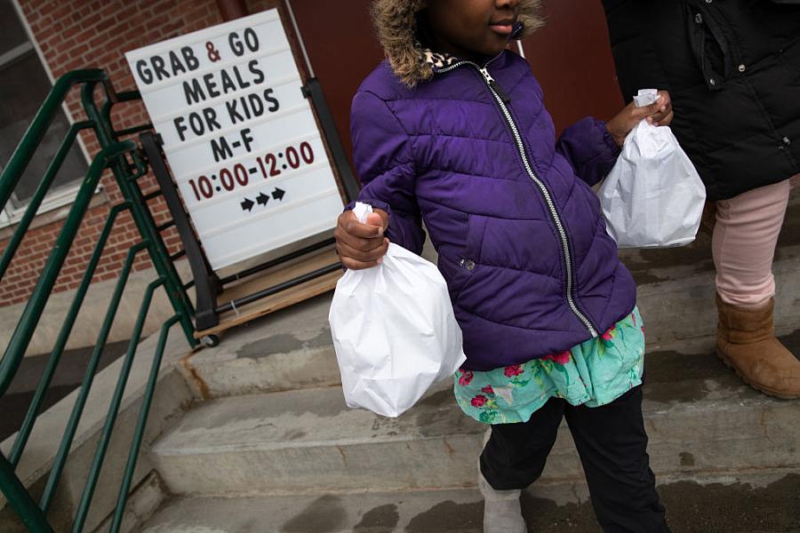 A student carries home bagged meals given out as part of a grab-and-go meal program run by public schools in Stamford, Connectic