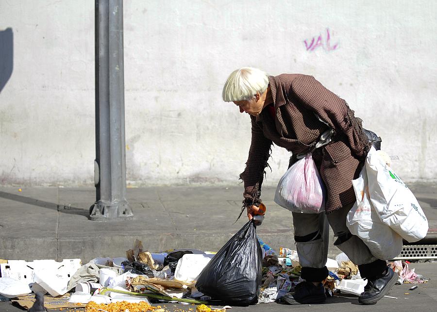 Photo: Woman picking trash on sidewalk. How poverty lowers your IQ