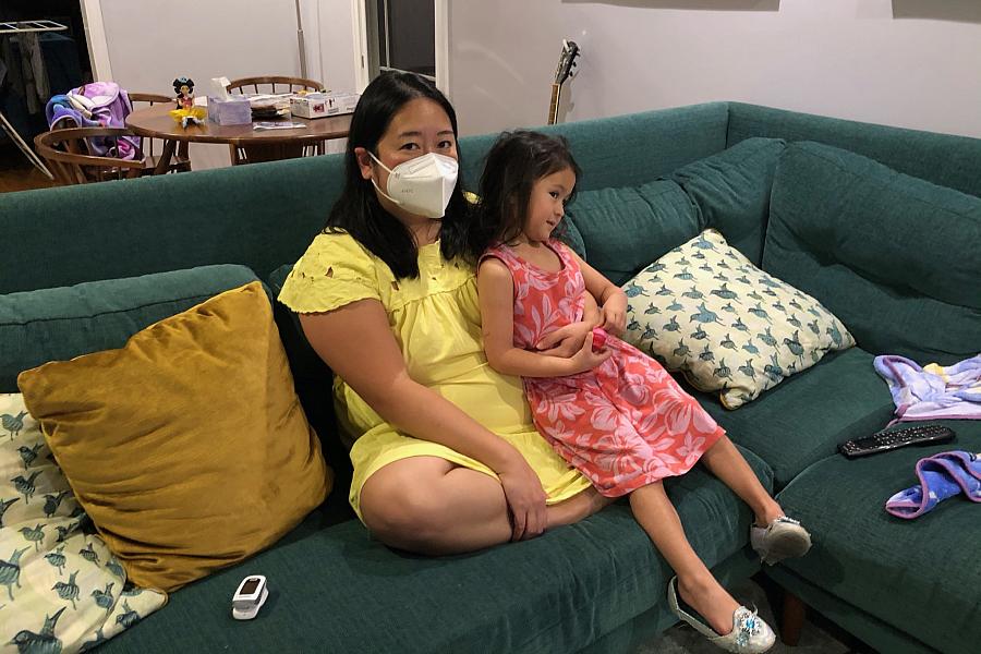 Anna Almendrala takes a short break from her oxygen concentrator to watch TV with her daughter, Marigold "Goldie" Ganz, three da